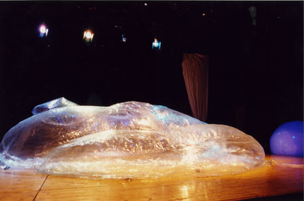 PREMIO MUSA 2004. Part 1 of a trilogy, “Oirat” explores three themes that run through the travel experience by using three different forms of representation. Part 1 comes in the form of a contemporary opera, and deals with migration as one form of travel experience, a quest fueled by hope, where projections of the traveler’s desired obscure and blot out everything else. OIRAT is the story of a RUBBER DINGHY, an object that seems to breathe in and out, just like humans, and which takes on different forms depending on the hopes of its passengers. The rubber craft encapsulates all of the forms of metamorphosis, not only those of human beings and nature in general, but also those of inanimate objects in a state of flux and capable of recounting a metaphor of life. The opera lasts 45 minutes and features a troupe of 18 musicians and 5 vocalists. Music: Alexander Peçi; Conducted by: Zhani Ciko; Wardrobw: Anne Brault ; Actors: Rovena Kureta, Etleva Golemi, Ferdinando Cordeiro Opa, Alexei Ivanov, Alma Strazimiri, Avni Shehu, Agim Duro, Shqipe Mingomataj; Amra Contemporary Music Orchestra.Text by: Valerio Ferrari; Translation by Maurici Pla.